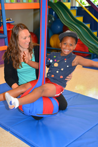 young boy on swing with therapist