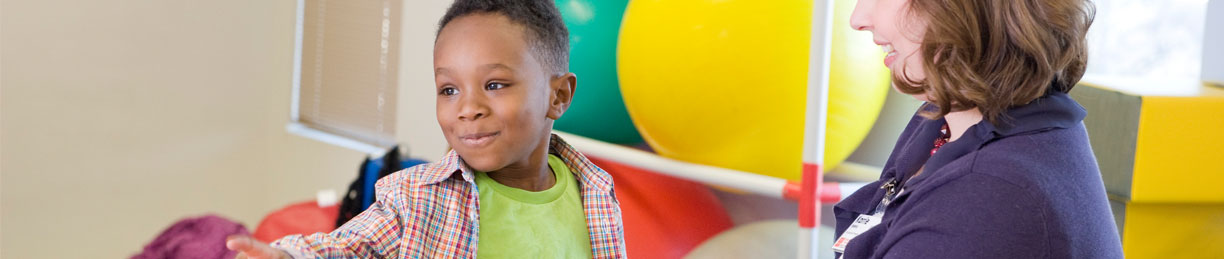 image of boy with therapist on therapy ball