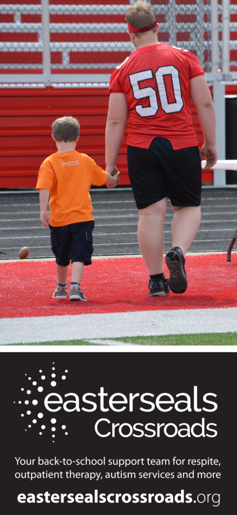 child walking hand-in-hand with football player