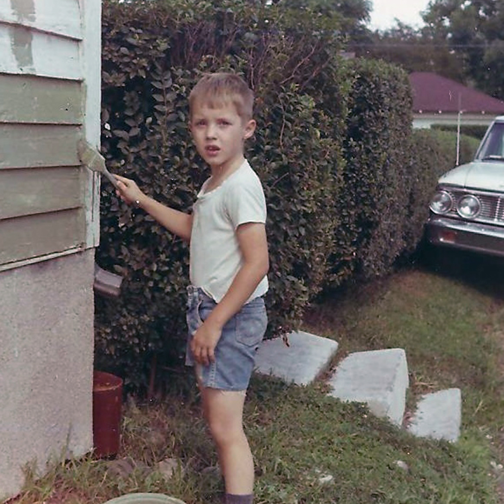 image of Richard painting on the side of a house in the 1960s