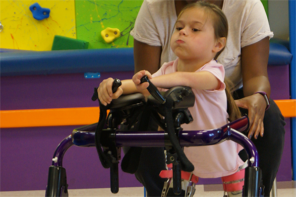 Girl walking with a walker.