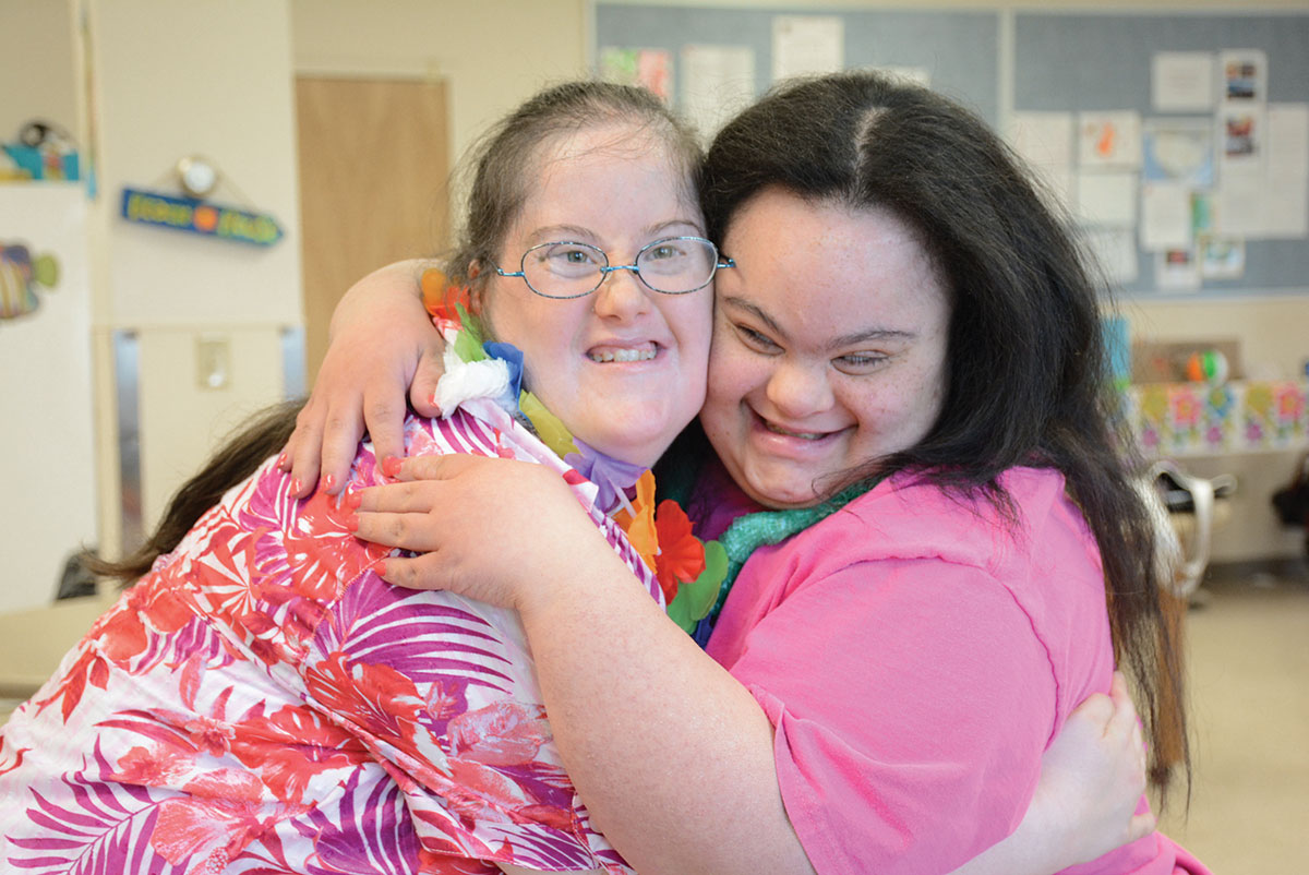 Two ladies are smiling and hugging.