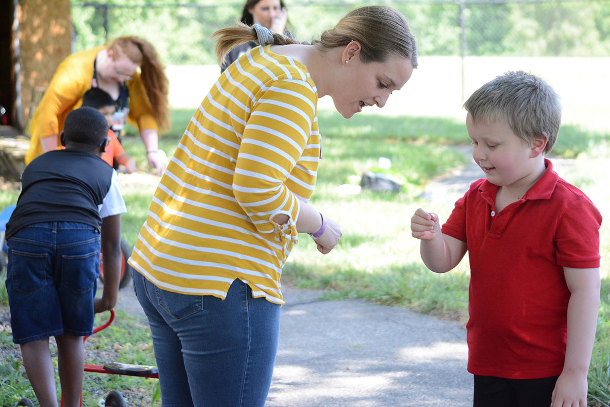 Group of people outside. Boy showing something in his hand to a lady.