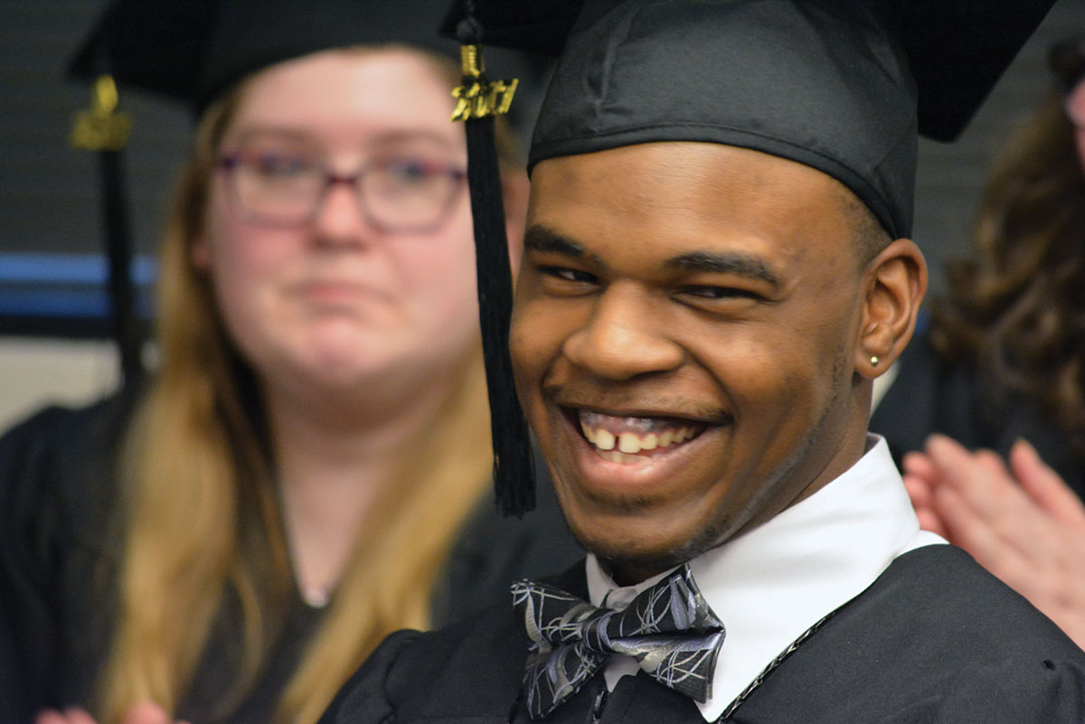 Man smiling in a graduation gown.