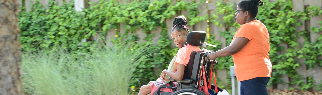 a lady pushing a girl in a wheelchair