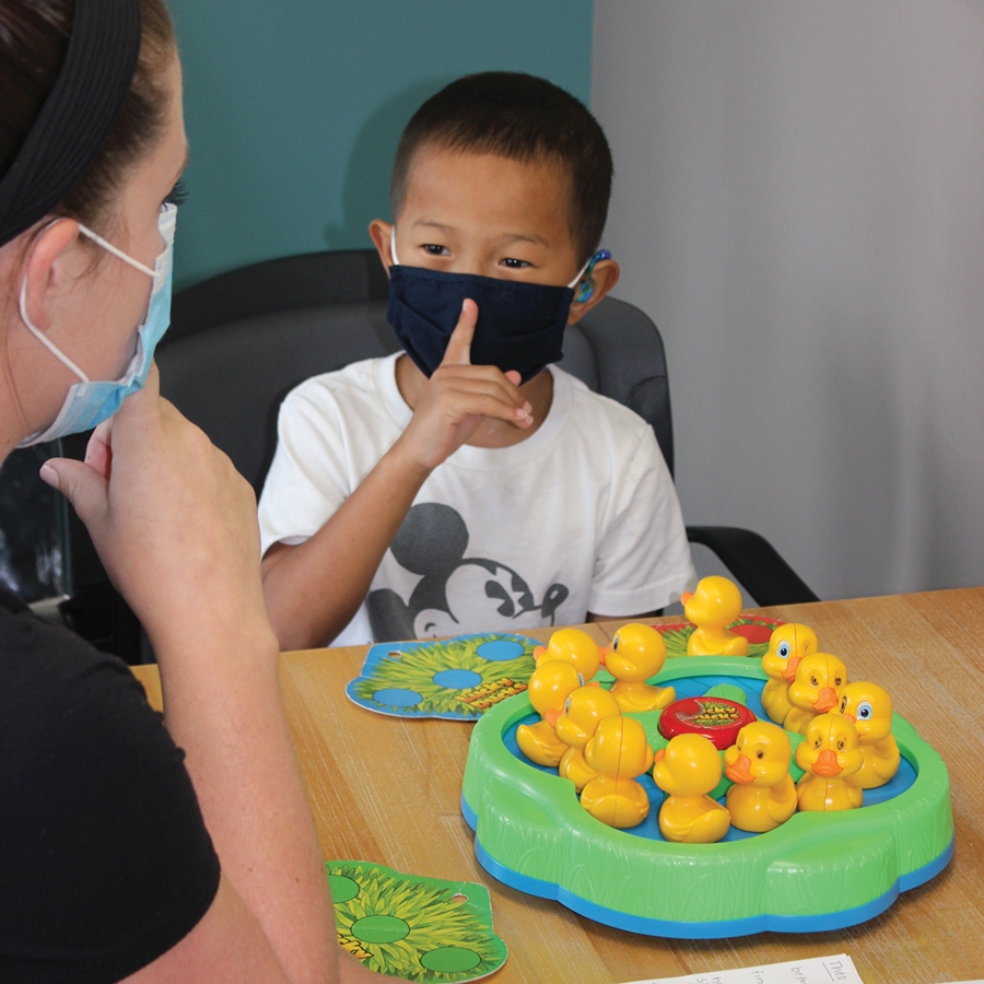 Boy and lady wearing masks with finger held to mouth