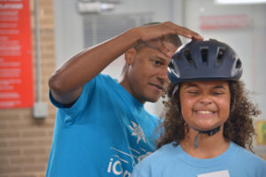 Michael Ferron with iCan Bike participant securing helmet