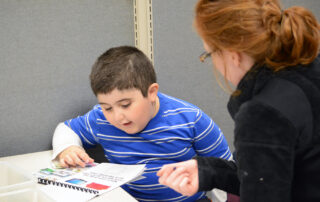 young boy reading with therapist
