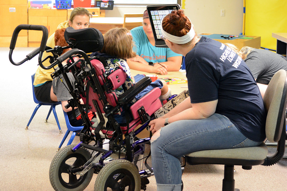 A girl and teachers learning on a special touch screen.