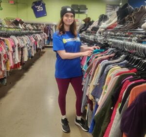 Woman working with a rack of clothes at a store.