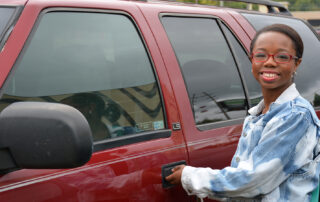 young driver standing next to her car