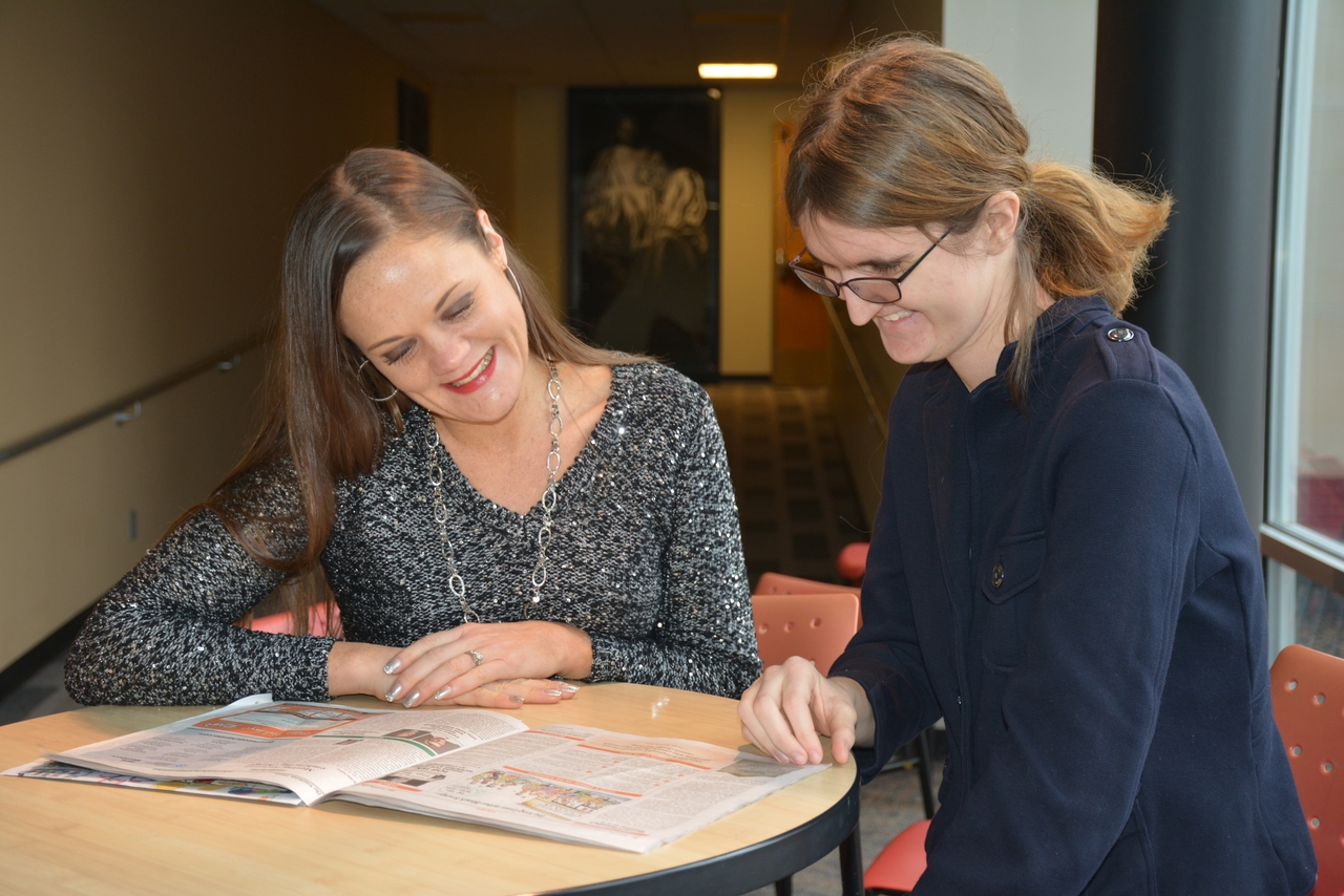 two women at a table, looking at books