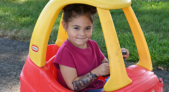 young girl smiling in a play car