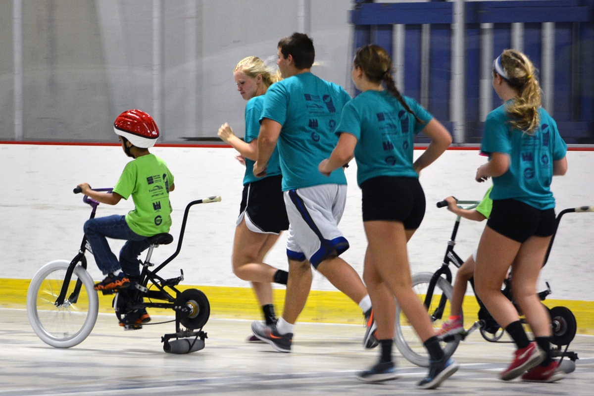icanbike2 ESC team members running along side of kids riding bikes on ice rink
