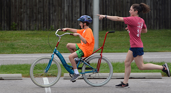 volunteer spotters supporting a child learning to ride a bike