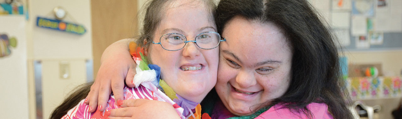 Two ladies smiling and hugging.