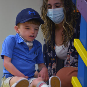 young boy on slide with therapist